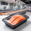 Filetes de salm&oacute;n fresco en una bandeja de PP negra sellada exhibida en una moderna secci&oacute;n de delicatessen de un supermercado